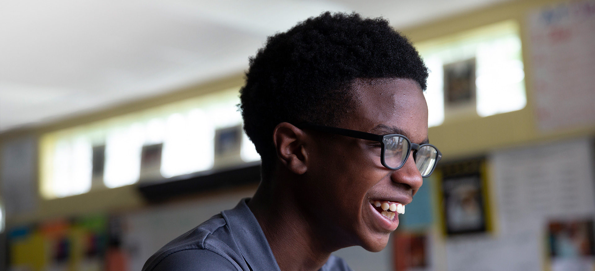 Student wearing glasses looking to the side and smiling.